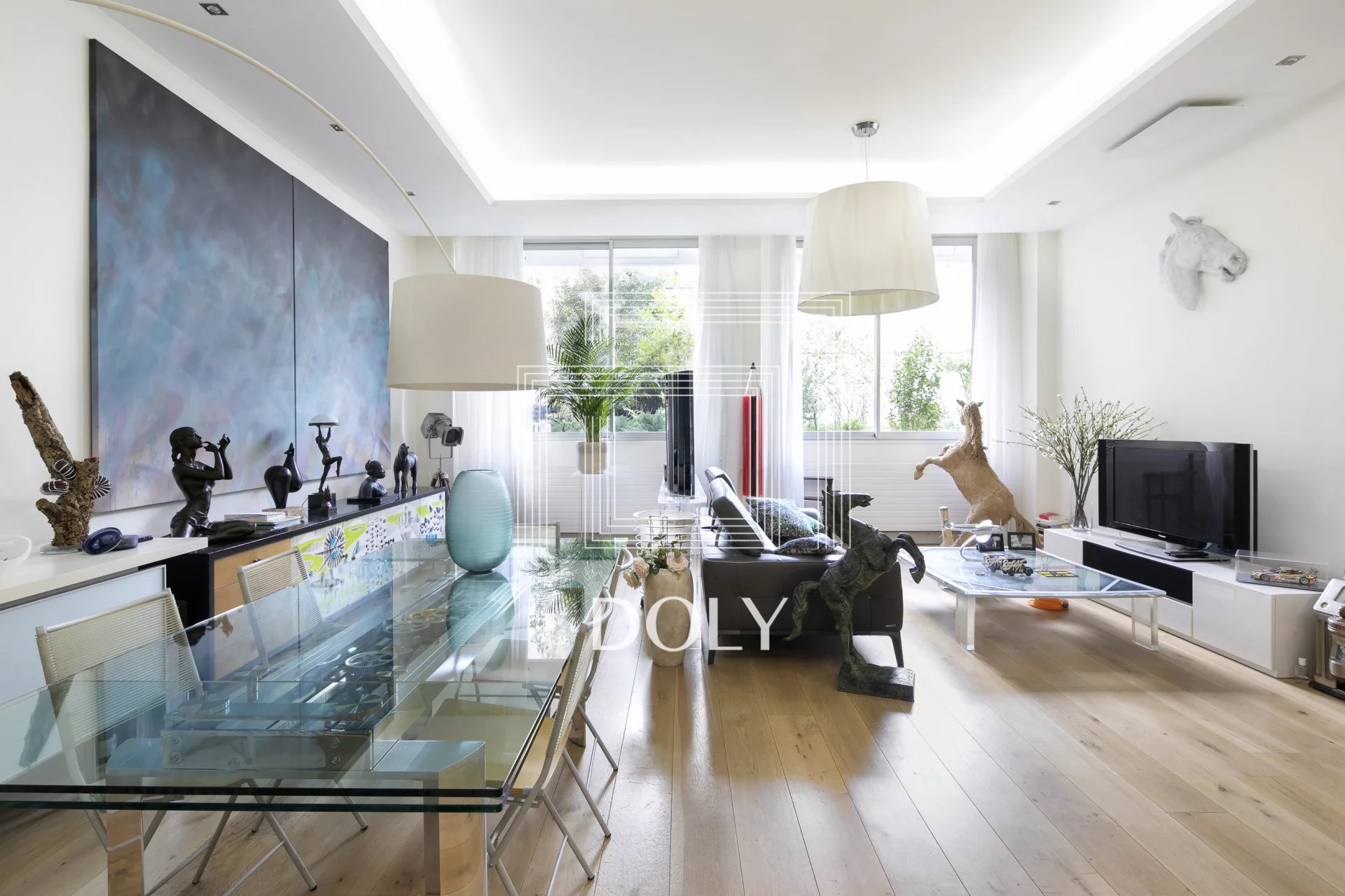 Appartement 3 pièces de 108 m² - Image de l'espace de vie, avec son beau parquet, son mobilier moderne et ses finitions modernes. Deux grandes fenêtres laissent entrer une lumière naturelle abondante.