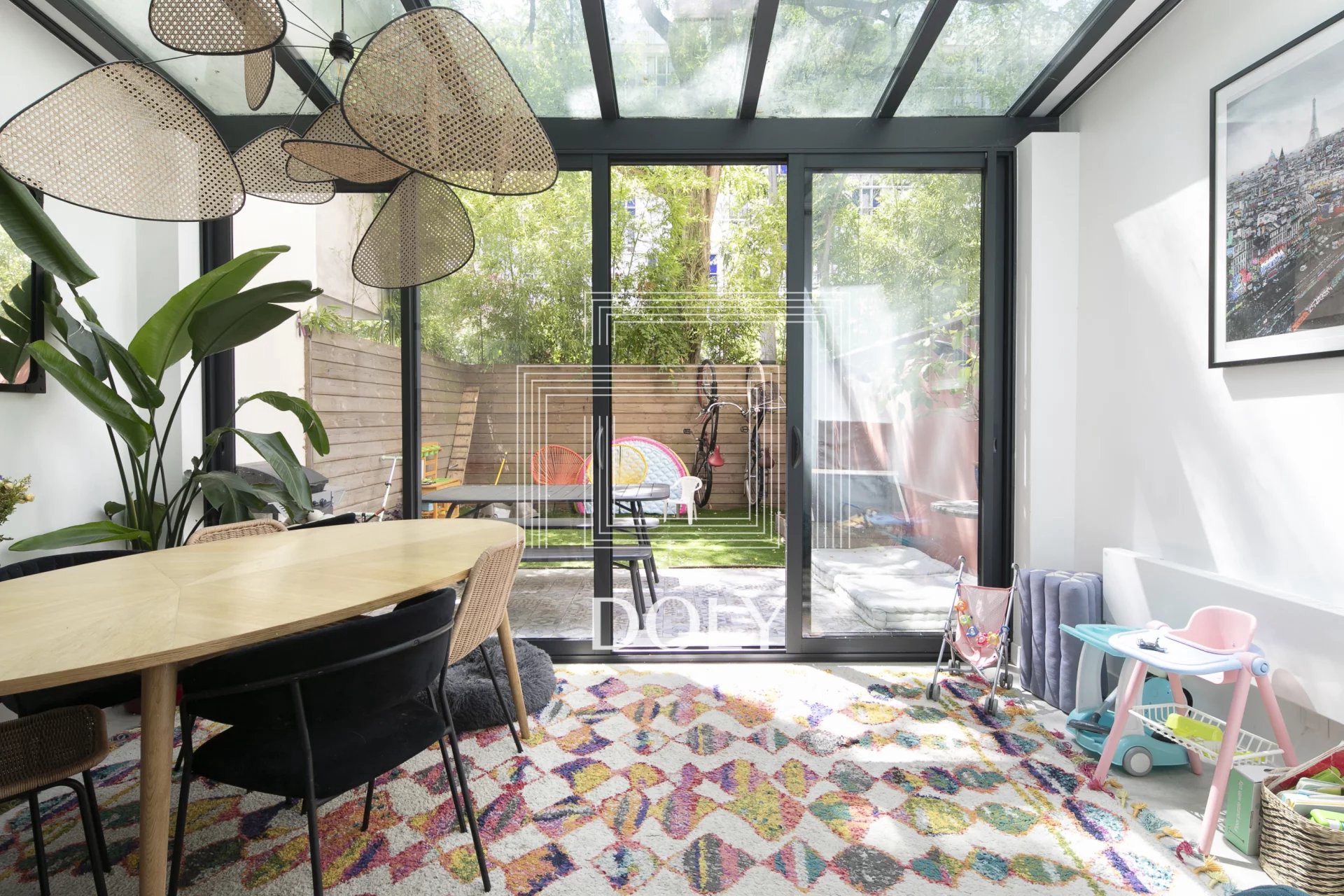 Appartement 3 pièces / 74 m² / Boulogne Billancourt L'image montre la véranda, meublée et dotée de baies vitrées et d'une verrière qui laisse entrer une belle lumière naturelle.