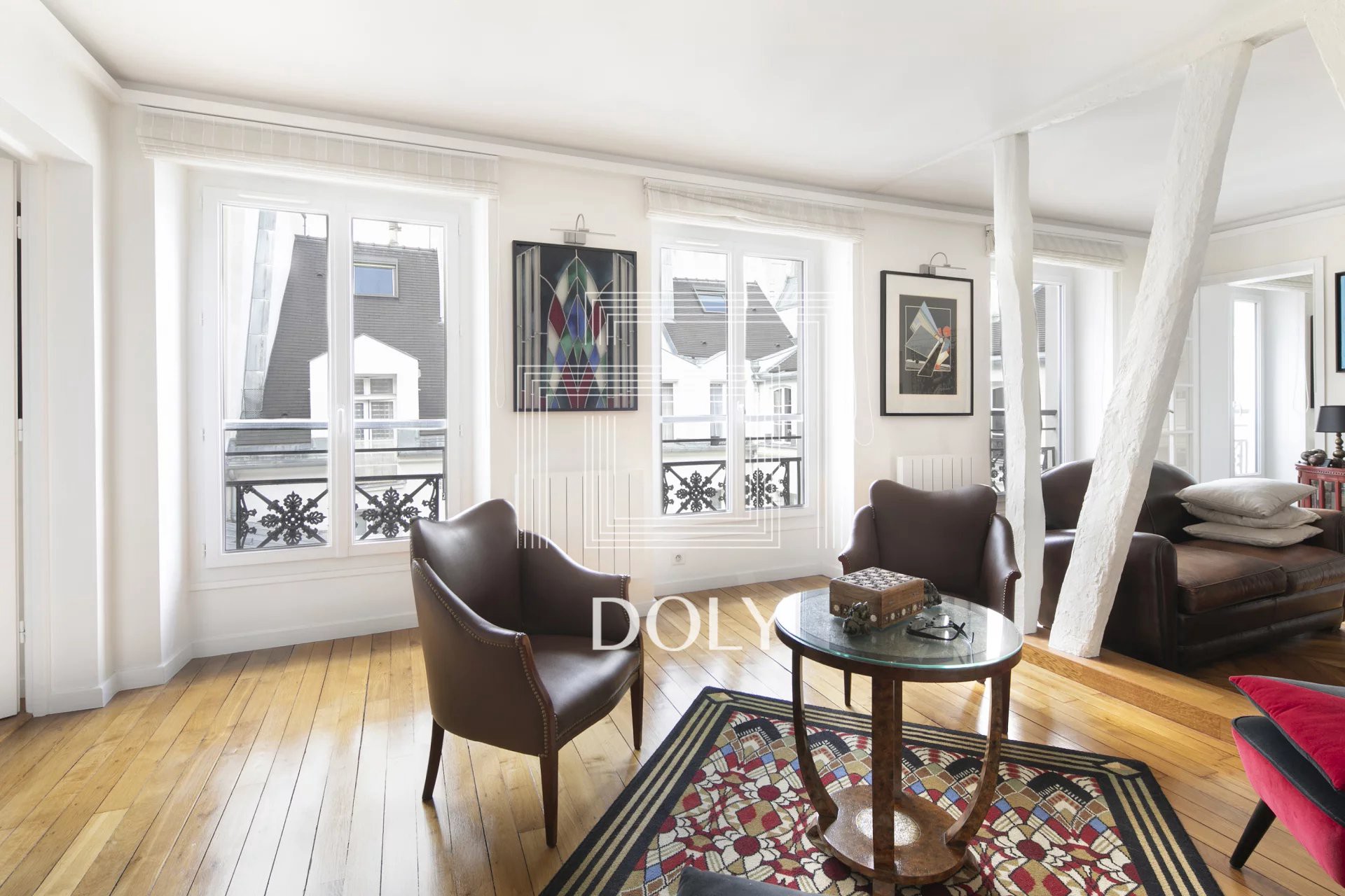 PARIS 75004 • Rue Saint-Antoine • Appartement 3 Pièces 74 m² - L'image montre l'espace de vie du logement, suffisamment spacieux pour accueillir une table basse et un canapé. Les trois portes-fenêtres laissent entrer la lumière naturelle.
