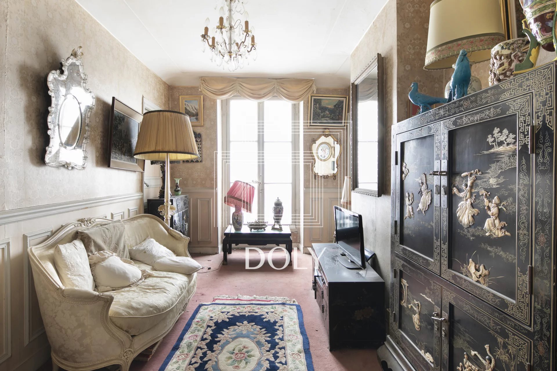 Trois pièces à rénover au cœur des Batignolles - L'image montre l'espace de vie, avec placard, canapé et finitions murales classiques.