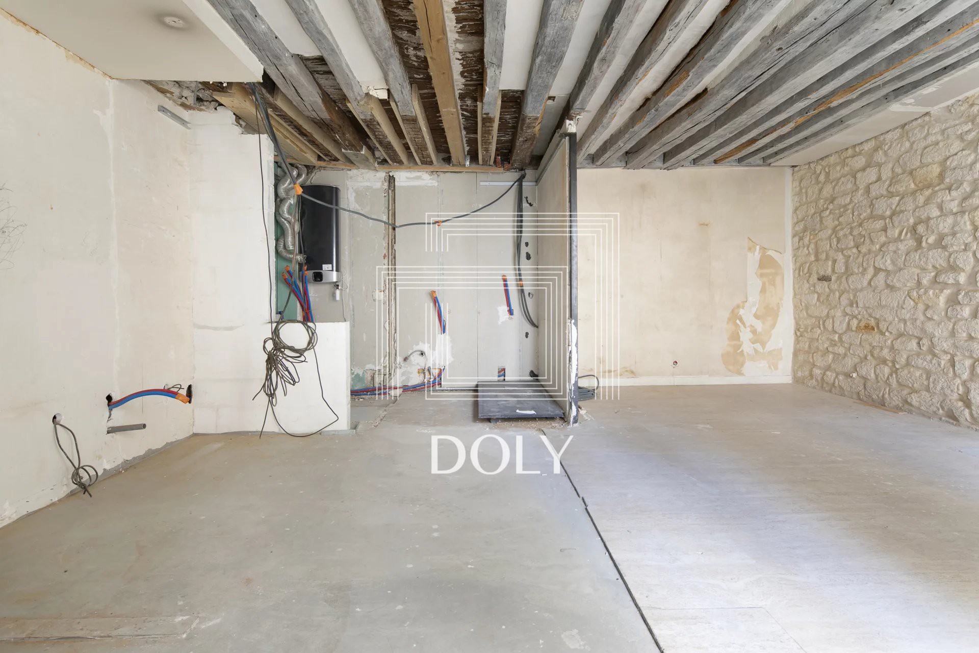 Appartement 2 pièces 55 m² // Rue Vieille du Temple // Le Marais - Intérieur de l'appartement, montrant l'espace de vie brut, non meublé. On aperçoit les murs en pierre apparente et les poutres en bois, prêts à être rénovés.