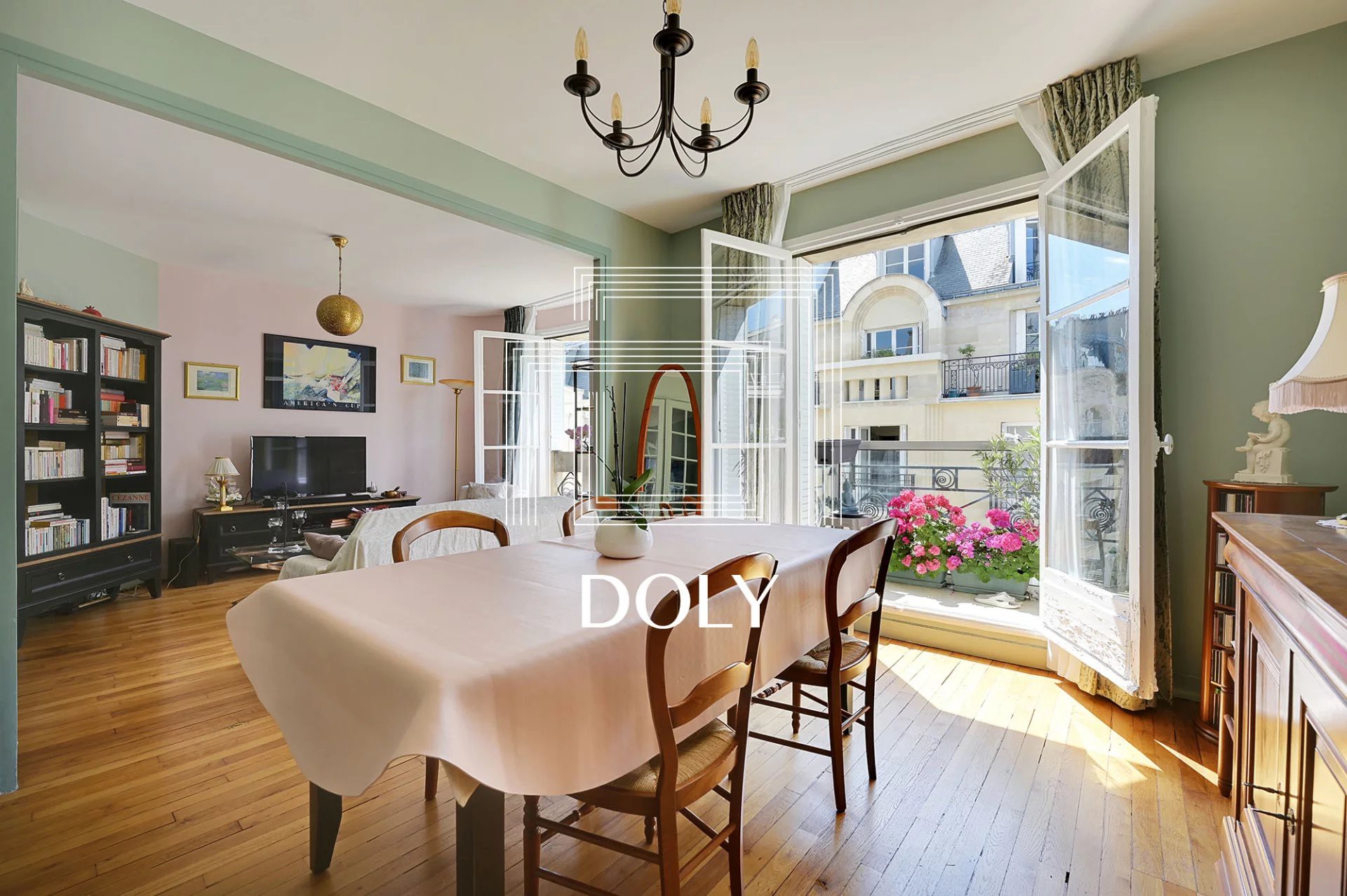 Appartement 4 pièces 86 m² // Square de Robiac // Métro Tour-Maubourg - L'image montre le séjour avec salle à manger, canapé et télévision. Deux grandes portes-fenêtres donnent accès au grand balcon.